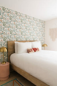 Queen sized bed light wood white linens and a love pillow