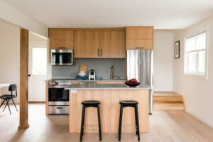 Kitchen with two stools next to an island. Light wood