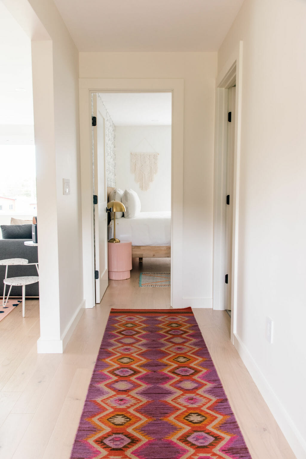 Hallway with red and orange patterned rug runner leading to bedroom.