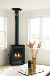 Gas burning fireplace with black pipe, tray with decorative plant on a coffee table